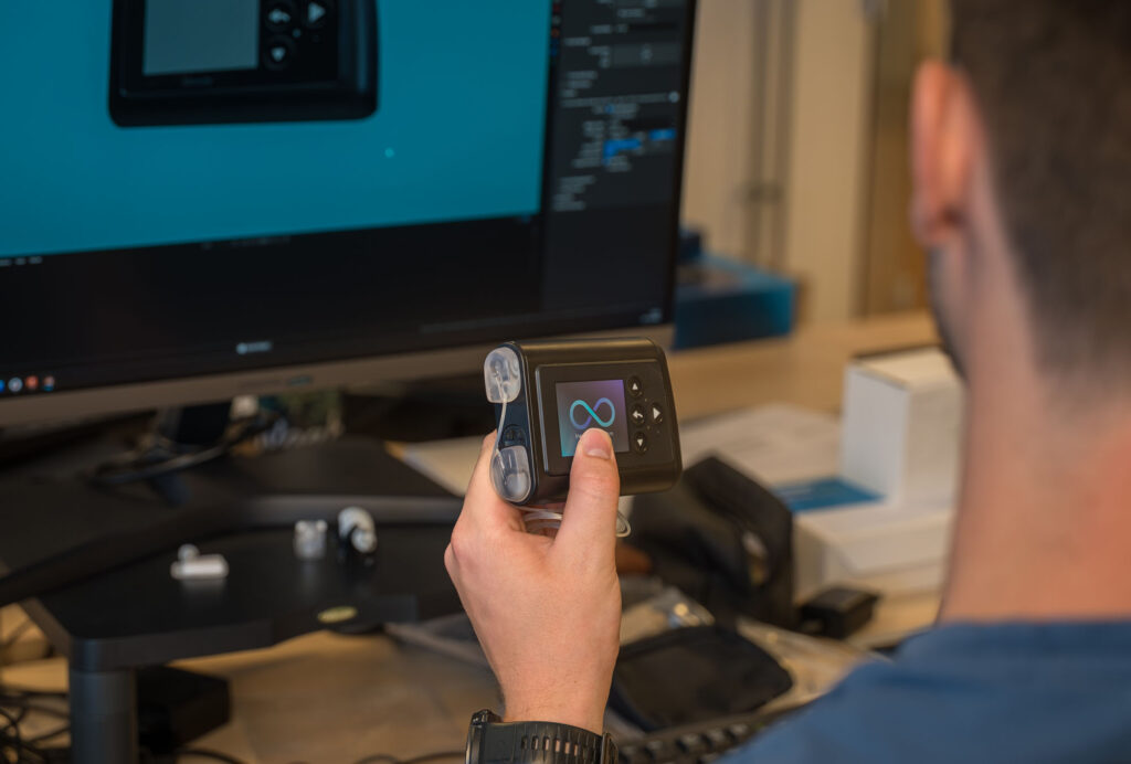 Een hand houdt de Inreda AP vast voor een beeldscherm met programmeercode